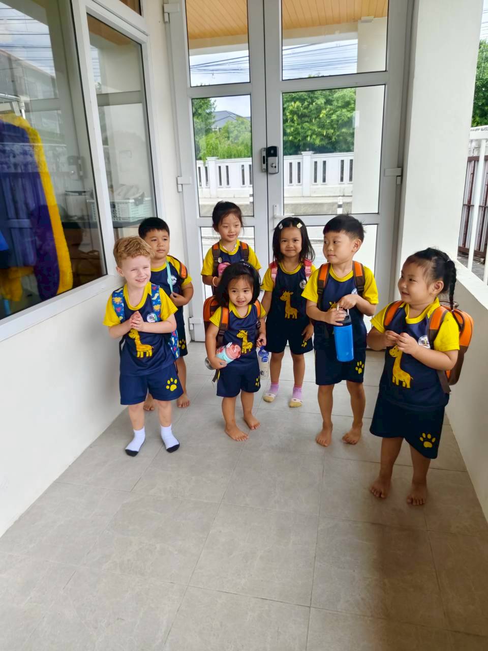 A group of smiling children wearing their SiLA backpacks in the school hallway