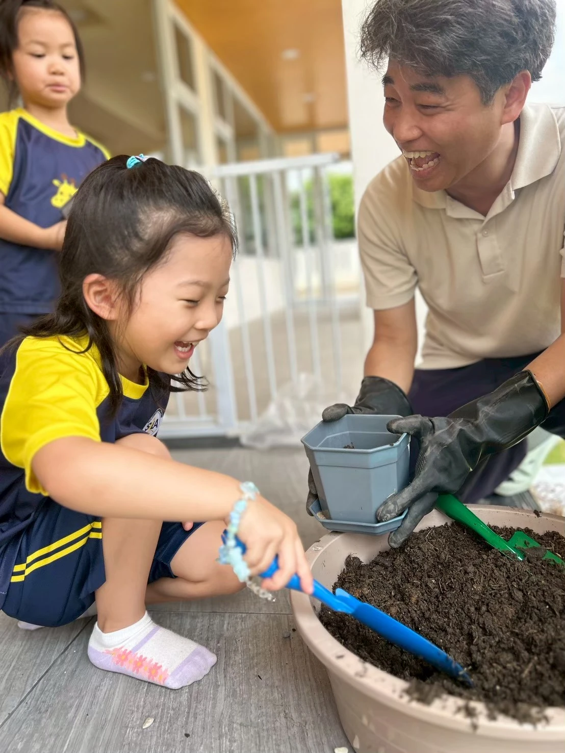 A teacher and child laughing together while potting a plant