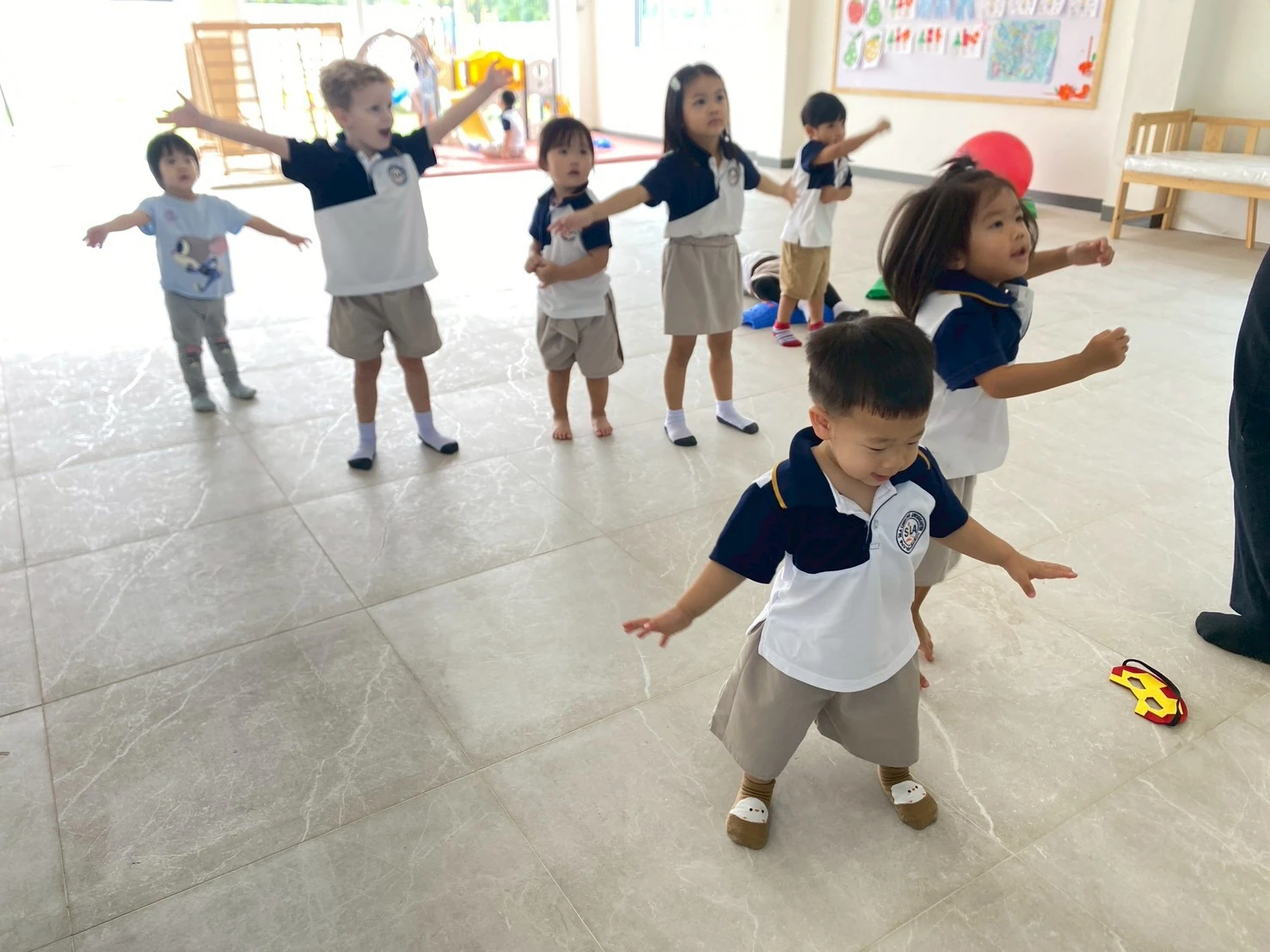 A group of children moving together with arms outstretched during a music and movement activity