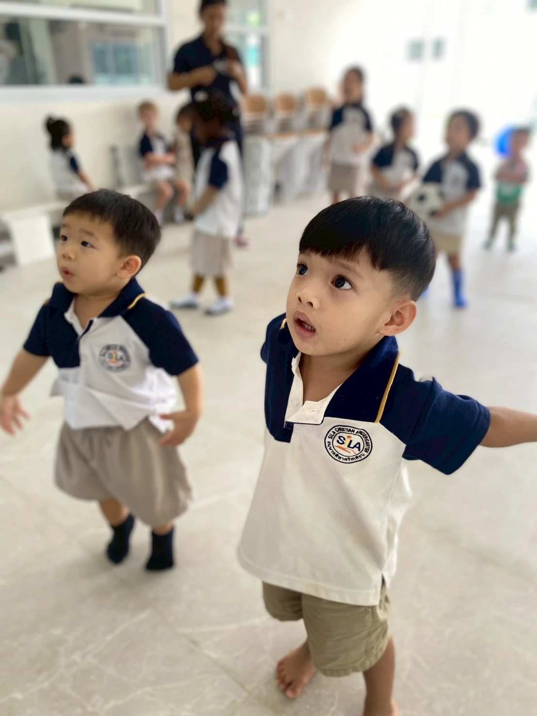 Two Nursery boys looking up together as they walk through a bright indoor play space
